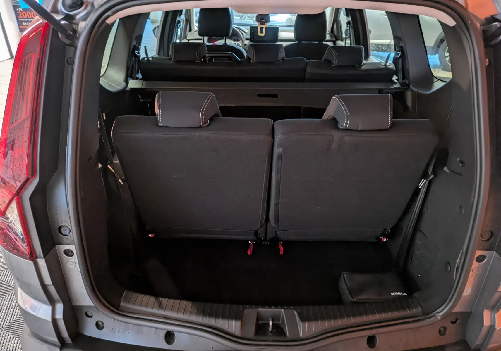 Vue arrière du coffre ouvert du Dacia Jogger gris schiste métal, montrant les sièges arrière rabattus et l’espace de chargement.