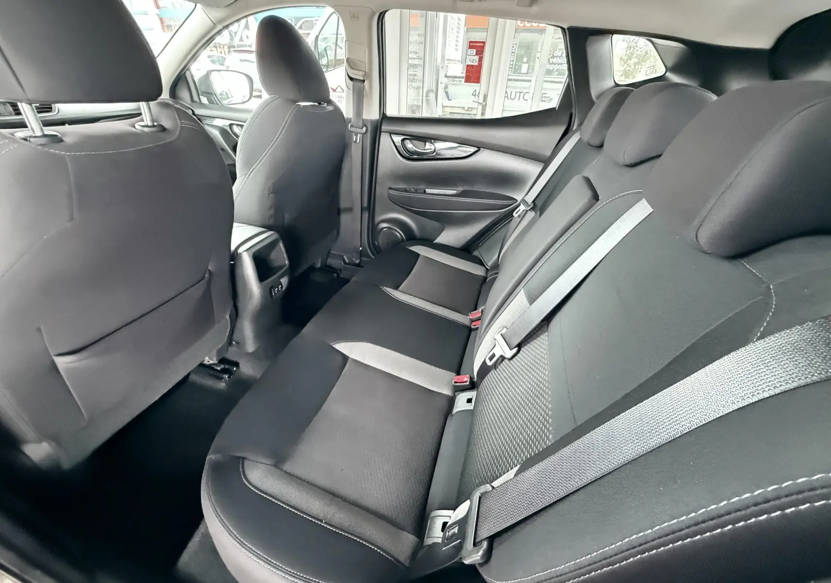 Intérieur arrière du Nissan Qashqai noir 2020, vue côté droit montrant les sièges en tissu noir avec ceintures grises.