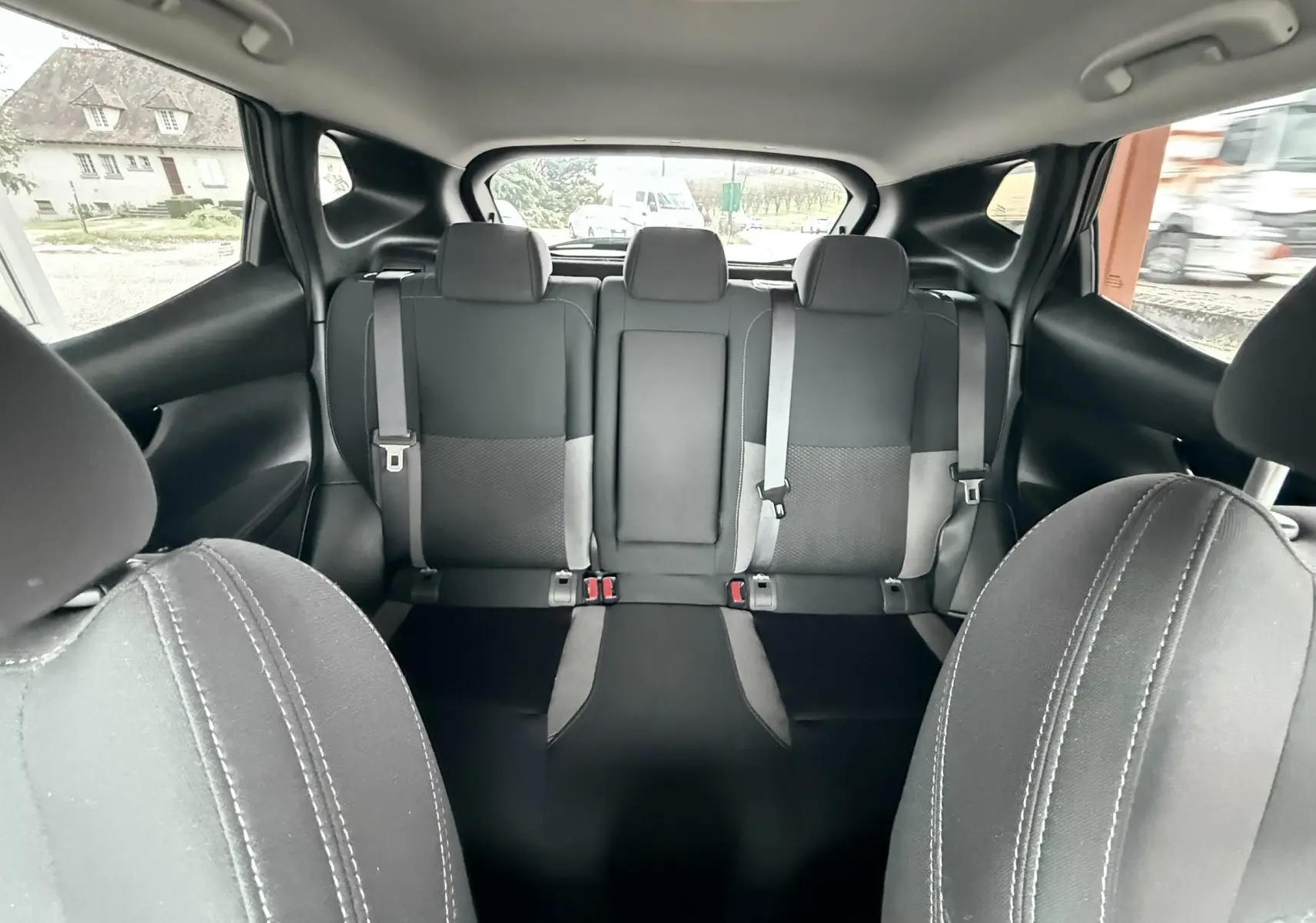 Vue intérieure arrière du Nissan Qashqai 2020 noir, montrant les sièges arrière en tissu noir et gris avec ceintures de sécurité.