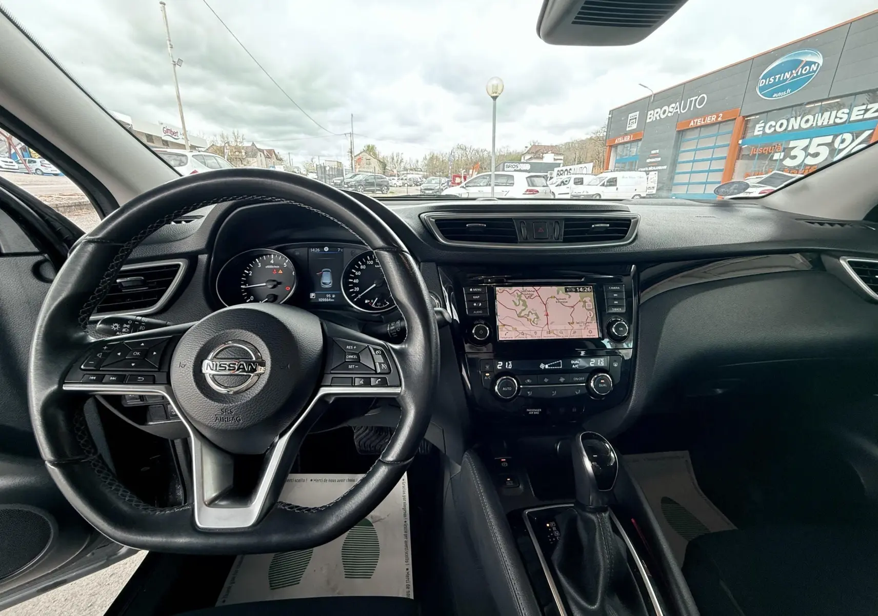 Vue intérieure du tableau de bord et volant Nissan Qashqai noir avec écran tactile affichant la navigation.