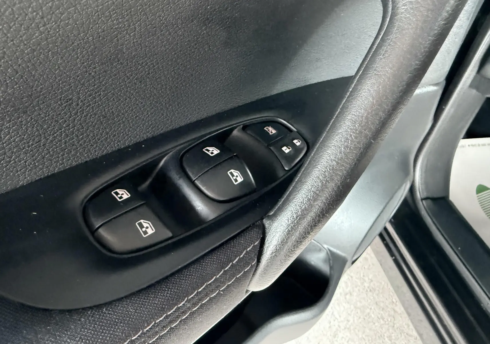 Gros plan sur les commandes de lève-vitres et verrouillage sur la porte avant gauche du Nissan Qashqai noir.