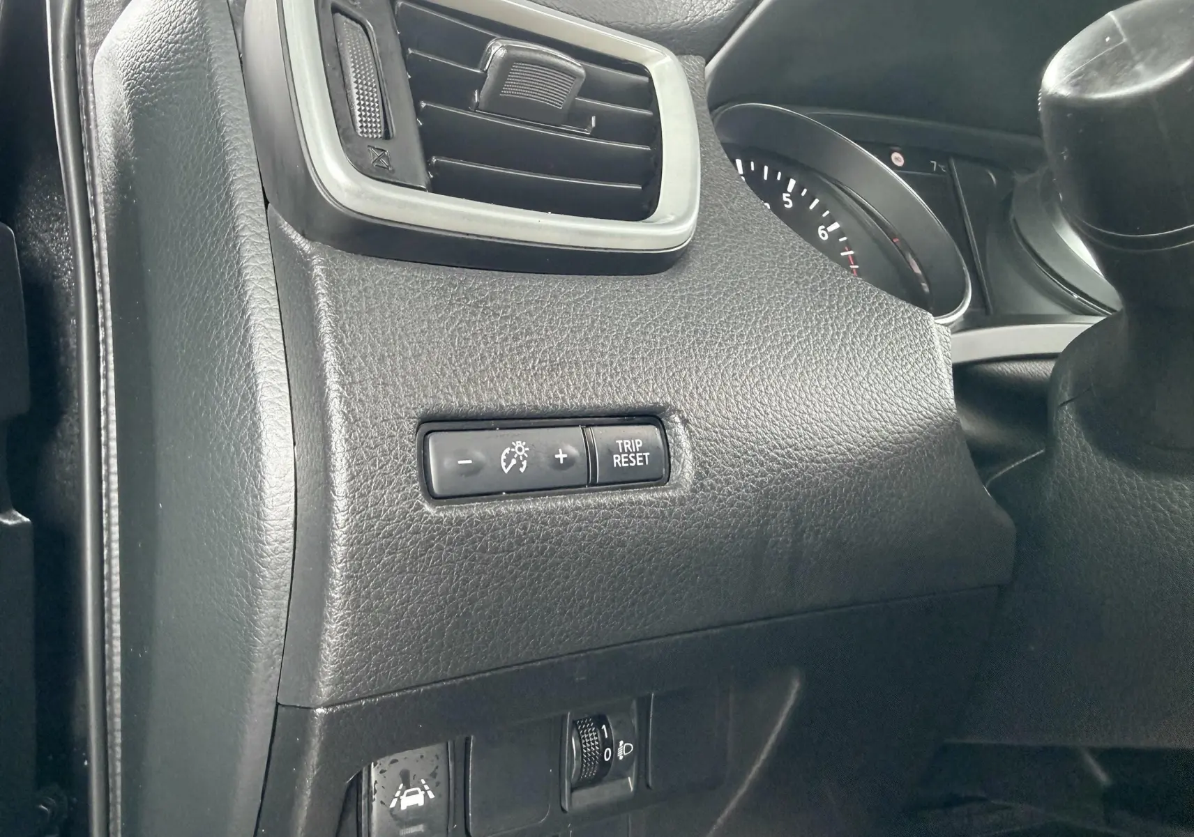 Détail du tableau de bord côté gauche du Nissan Qashqai noir, avec commandes d’éclairage et régulateur de vitesse.