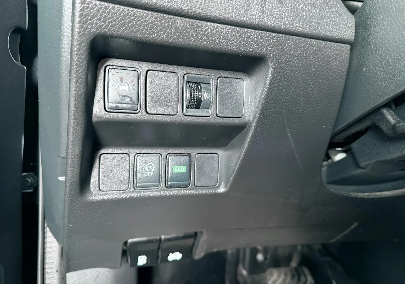 Vue intérieure côté gauche du tableau de bord noir avec commandes de réglage et boutons fonctionnels du Nissan Qashqai.