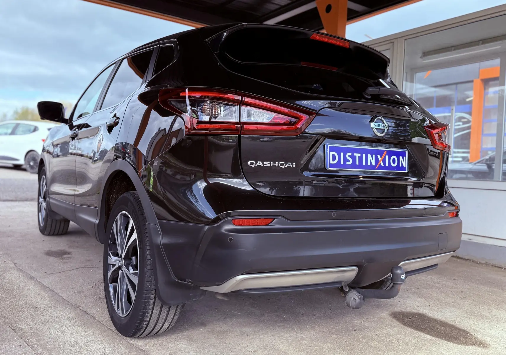 Vue 3/4 arrière droite d'un Nissan Qashqai noir avec attelage et feux arrière LED visibles.