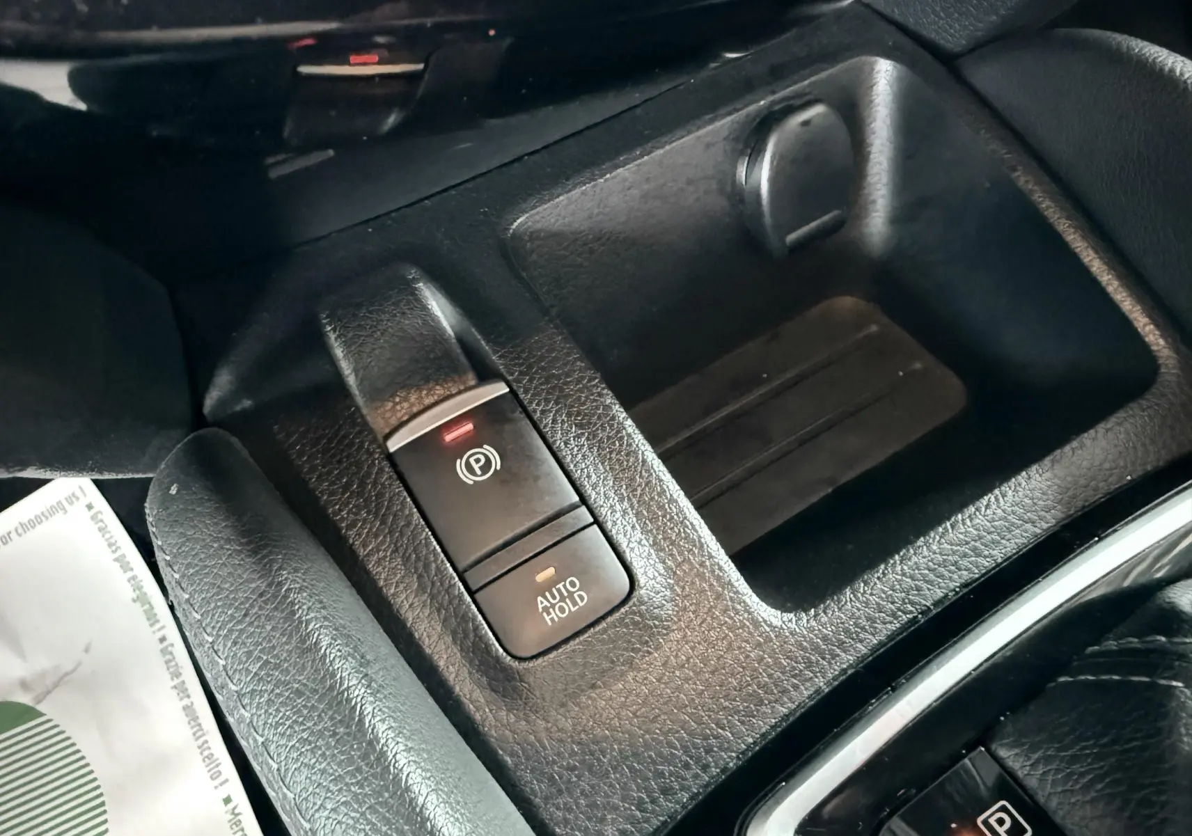 Gros plan sur la console centrale du Nissan Qashqai noir, montrant les boutons frein à main électrique et auto hold.