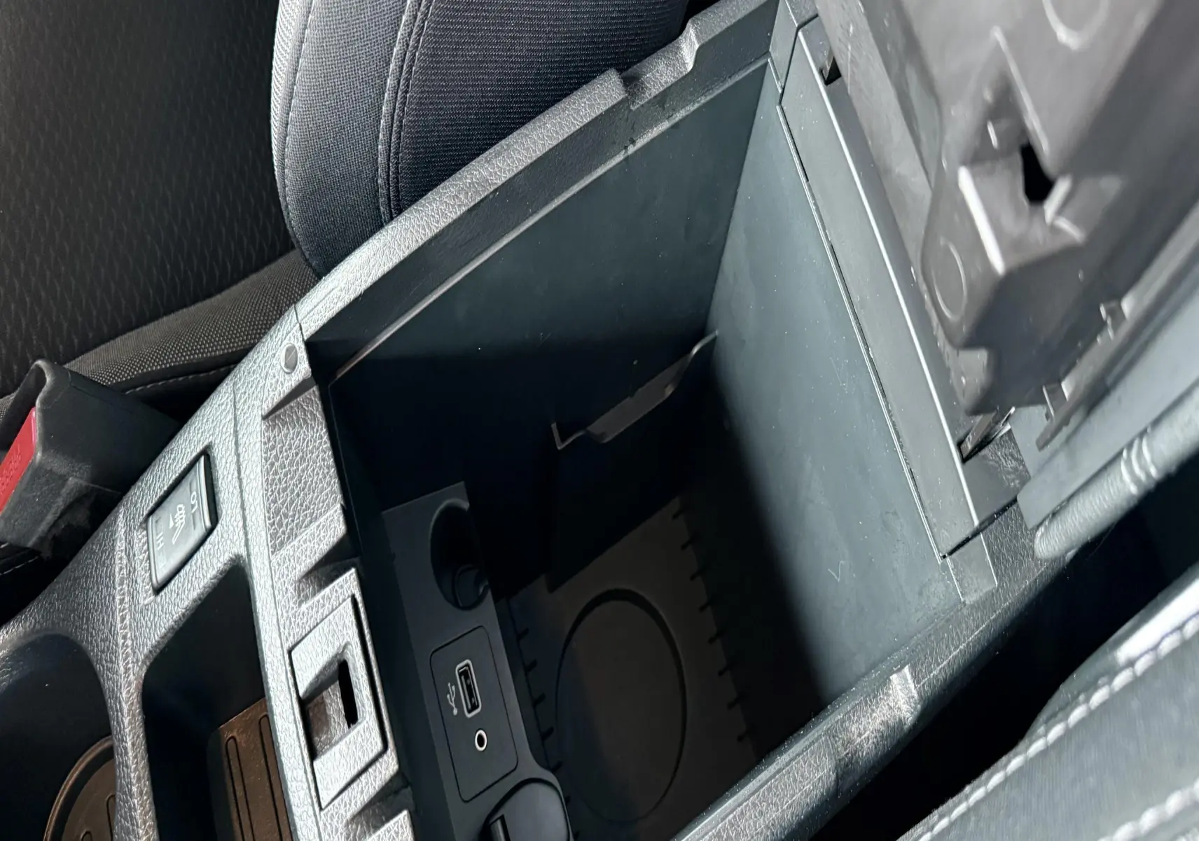 Vue rapprochée de la console centrale ouverte du Nissan Qashqai noir, montrant les ports USB et prise 12V.