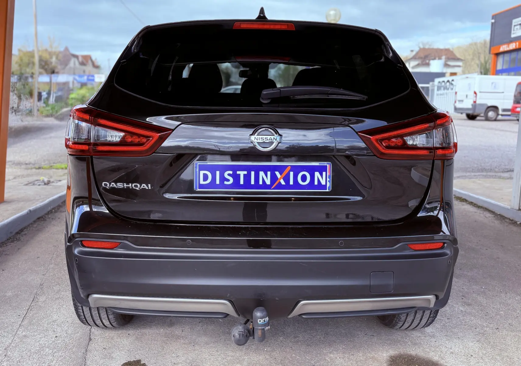 Vue arrière d'un Nissan Qashqai noir 2020 avec attelage et plaque Distinxion visible.