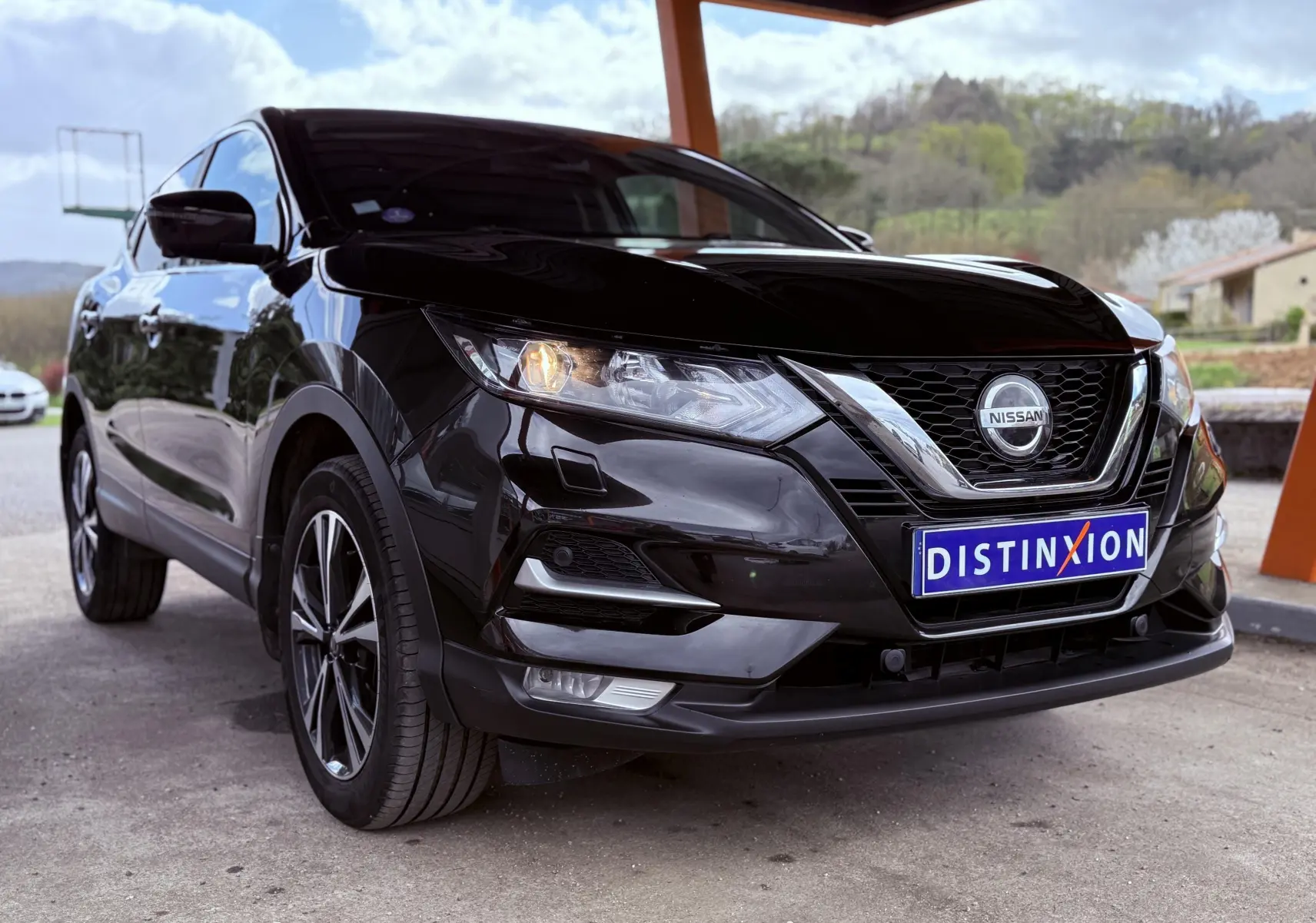 Nissan Qashqai noir vu en 3/4 avant droit, avec calandre chromée et plaque Distinxion visible.