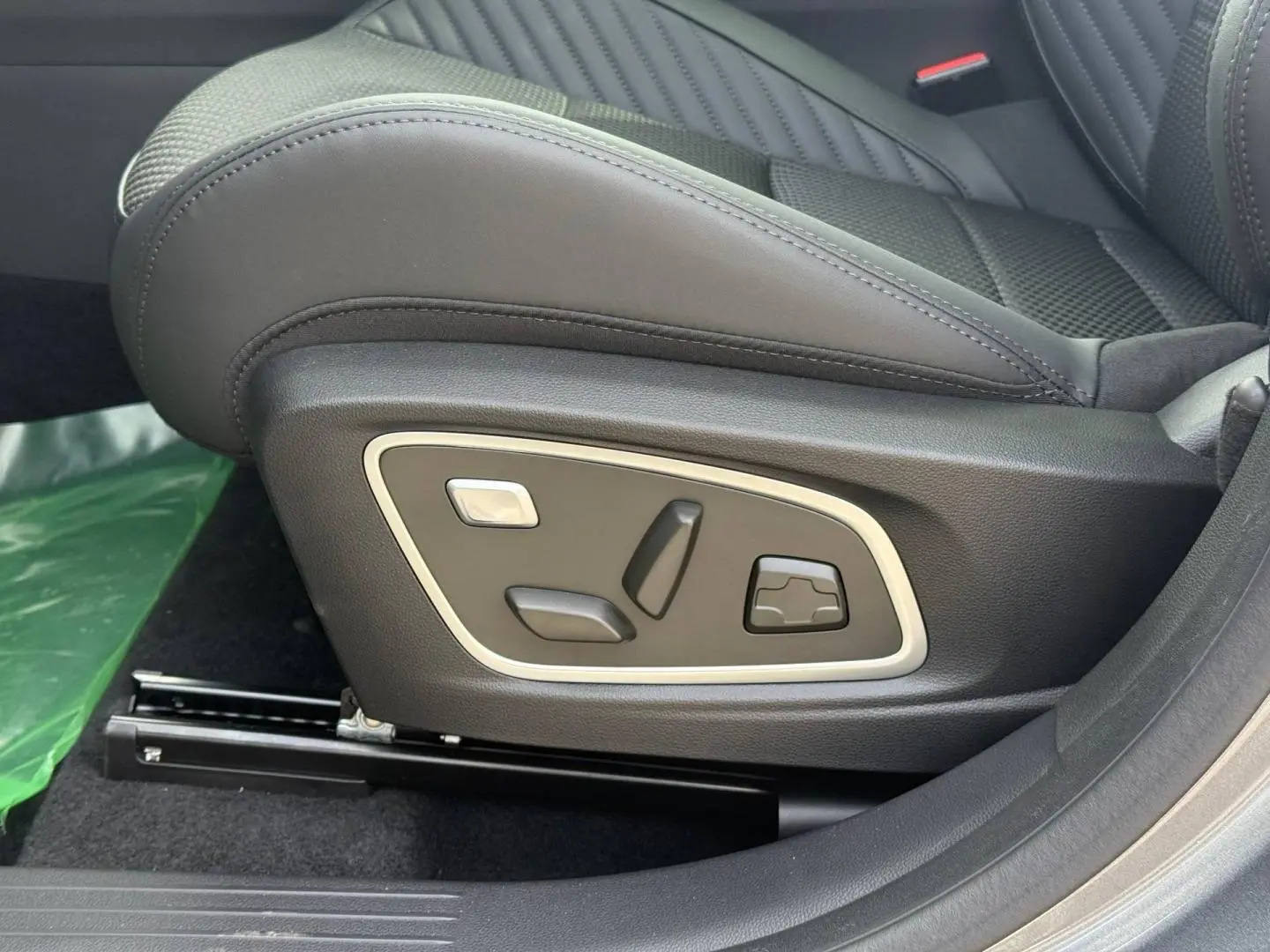 Gros plan sur les commandes électriques du siège conducteur en cuir noir du Renault Austral 2026, version hybride.