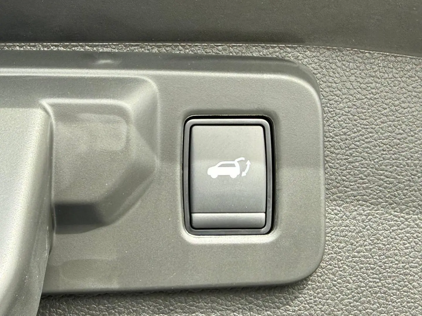 Bouton intérieur de commande d'ouverture électrique du coffre sur Renault Austral 2026, plastique gris texturé.