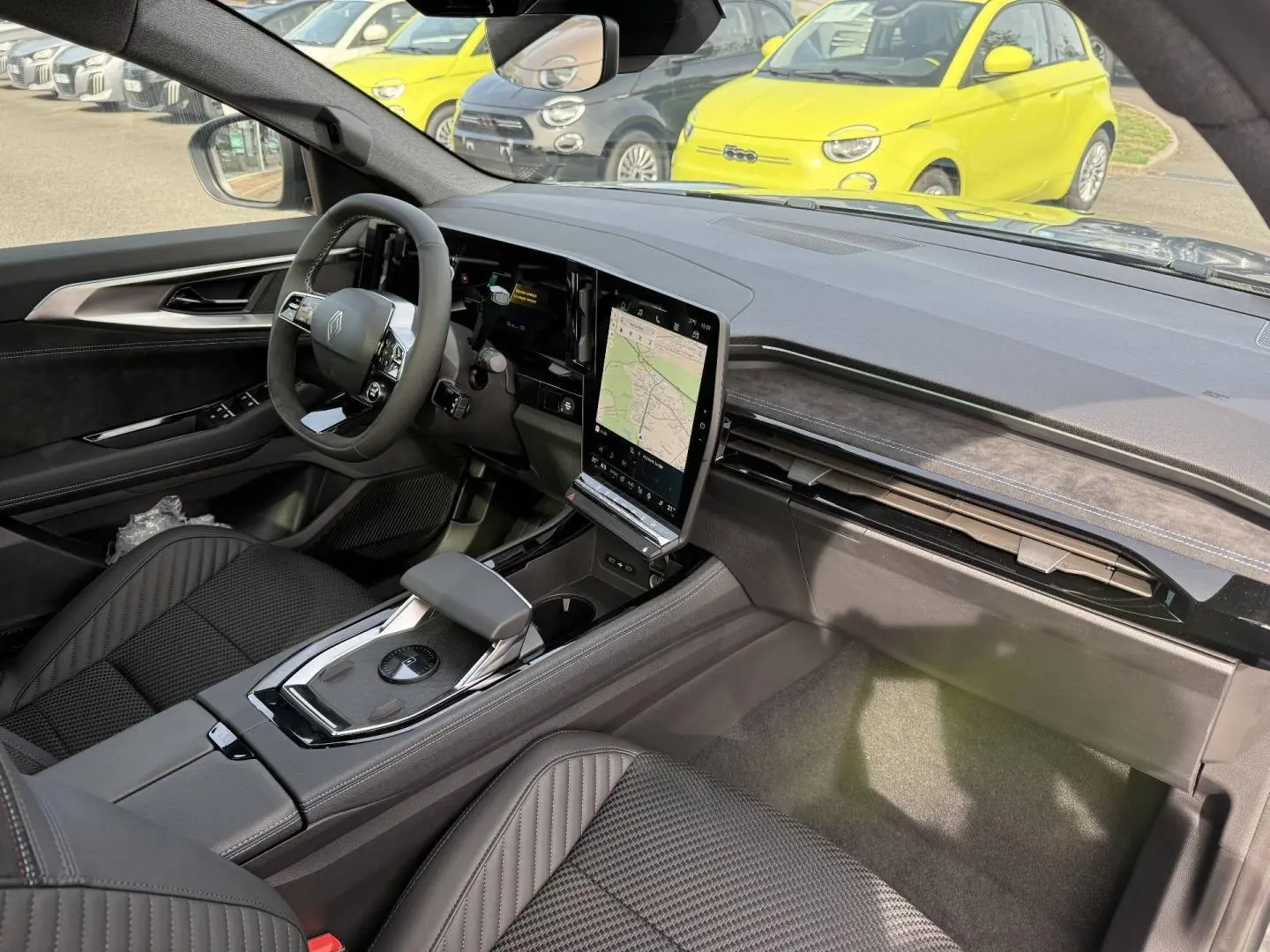 Vue intérieure côté conducteur du Renault Austral 2026, tableau de bord noir avec écran tactile vertical et sièges en tissu carbone Alcantara.