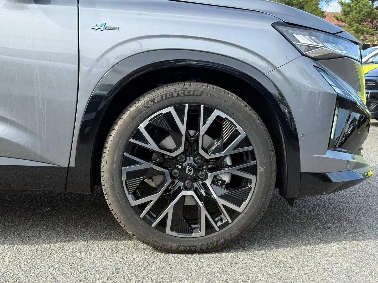 Gros plan sur la roue avant droite du Renault Austral gris Schiste satin avec jante alu noire et argentée, logo Alpine visible.