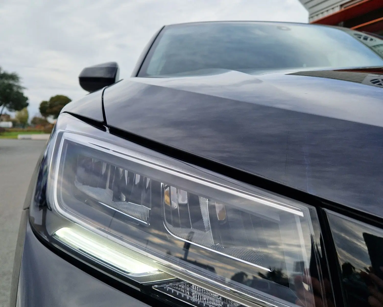 Gros plan sur le phare avant gauche d'un Audi Q2 35 TFSI noir mito metal, mettant en valeur ses lignes modernes et LED.