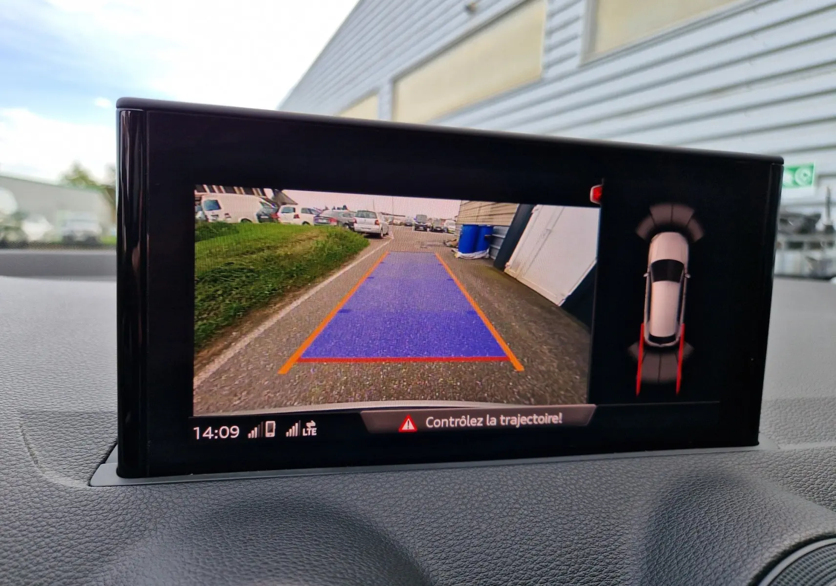 Écran multimédia affichant la caméra de recul avec trajectoire en bleu et vue 360° du Q2 noir mito metal en stationnement.