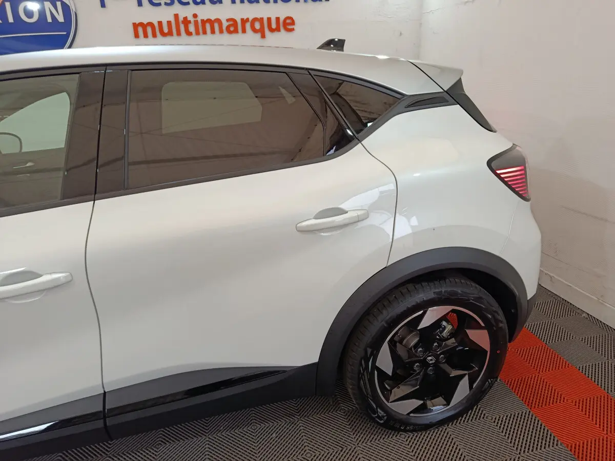 Vue latérale droite du Renault Captur blanc 2025, mettant en valeur la porte arrière et la roue arrière au design moderne.