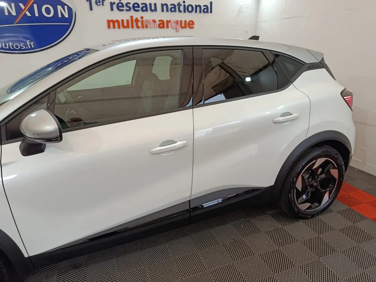 Profil côté gauche du Renault Captur blanc 2025, avec jantes noires et détails noirs sur les bas de caisse.