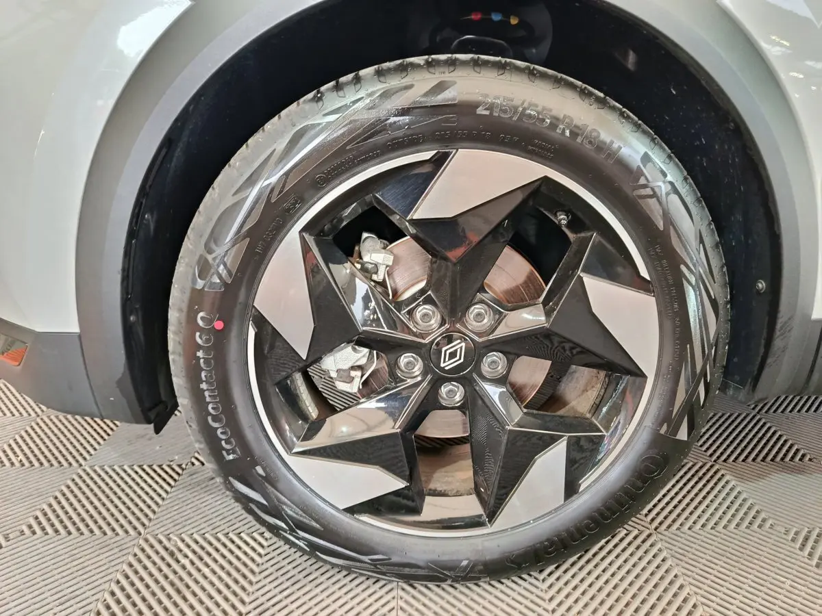 Gros plan sur la roue avant gauche du Renault Captur blanc 2025, mettant en valeur la jante noire et argentée au design géométrique.