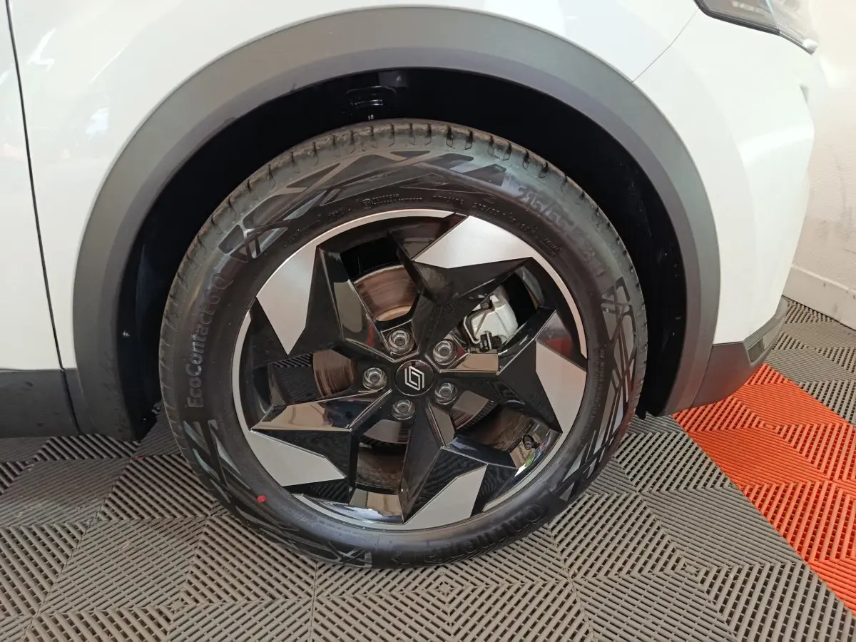 Gros plan sur la roue avant droite du Renault Captur blanc 2025 avec jante noire et argent au design géométrique.