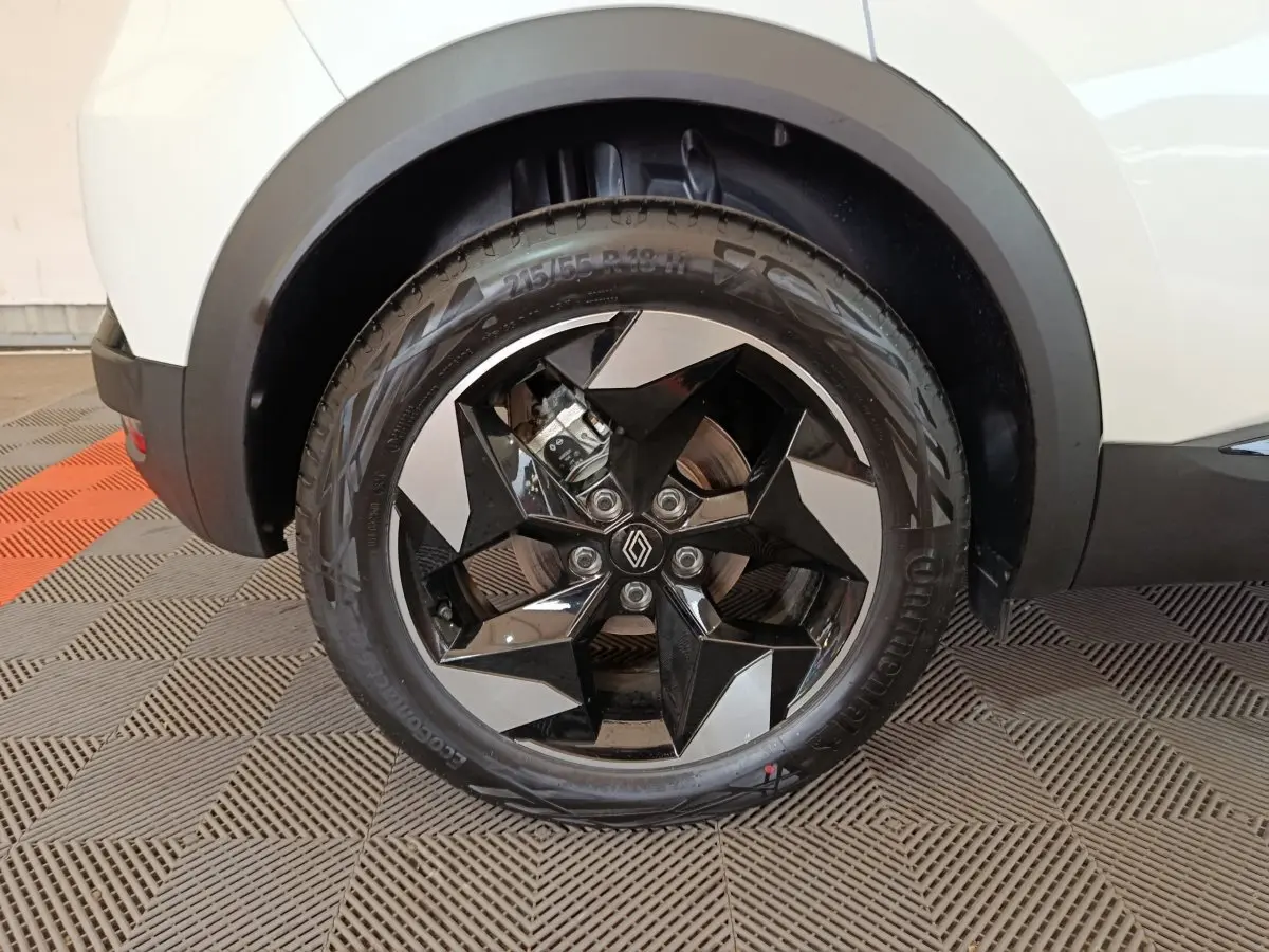 Gros plan sur la roue avant droite du Renault Captur blanc 2025, avec jante noire et argentée au design géométrique.