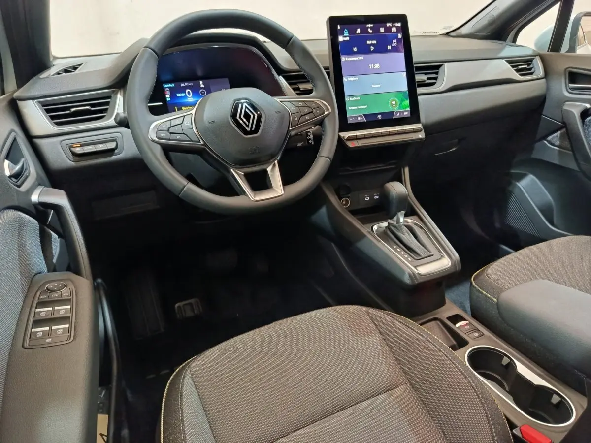 Intérieur noir du Renault Captur 2025, vue de face sur le volant multifonctions et l'écran tactile vertical central.