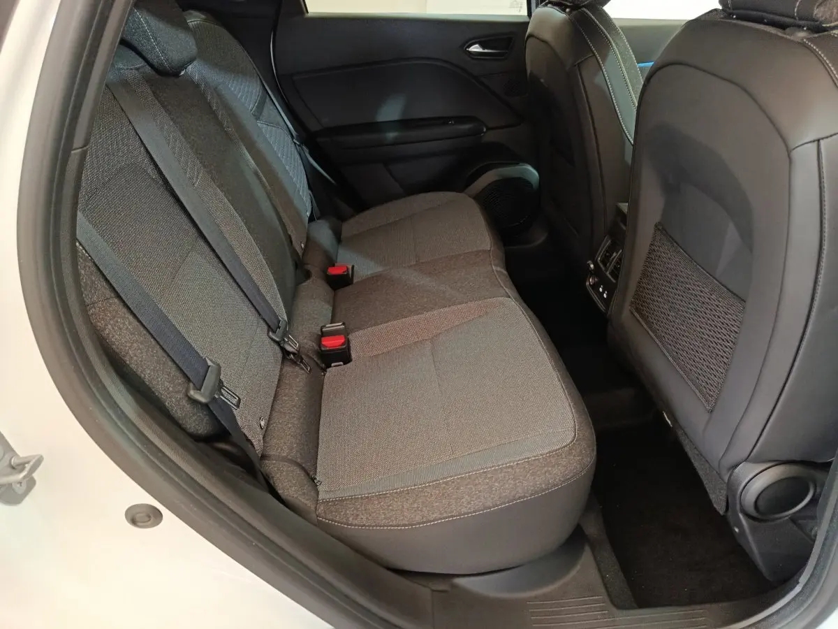 Vue latérale des sièges arrière gris foncé du Renault Captur blanc 2025, avec ceintures et porte ouvert côté gauche.