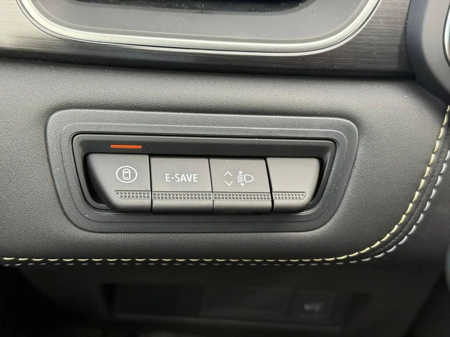 Gros plan sur les boutons de commande E-SAVE et réglage des phares dans l'habitacle noir du Renault Symbioz gris Rafale.