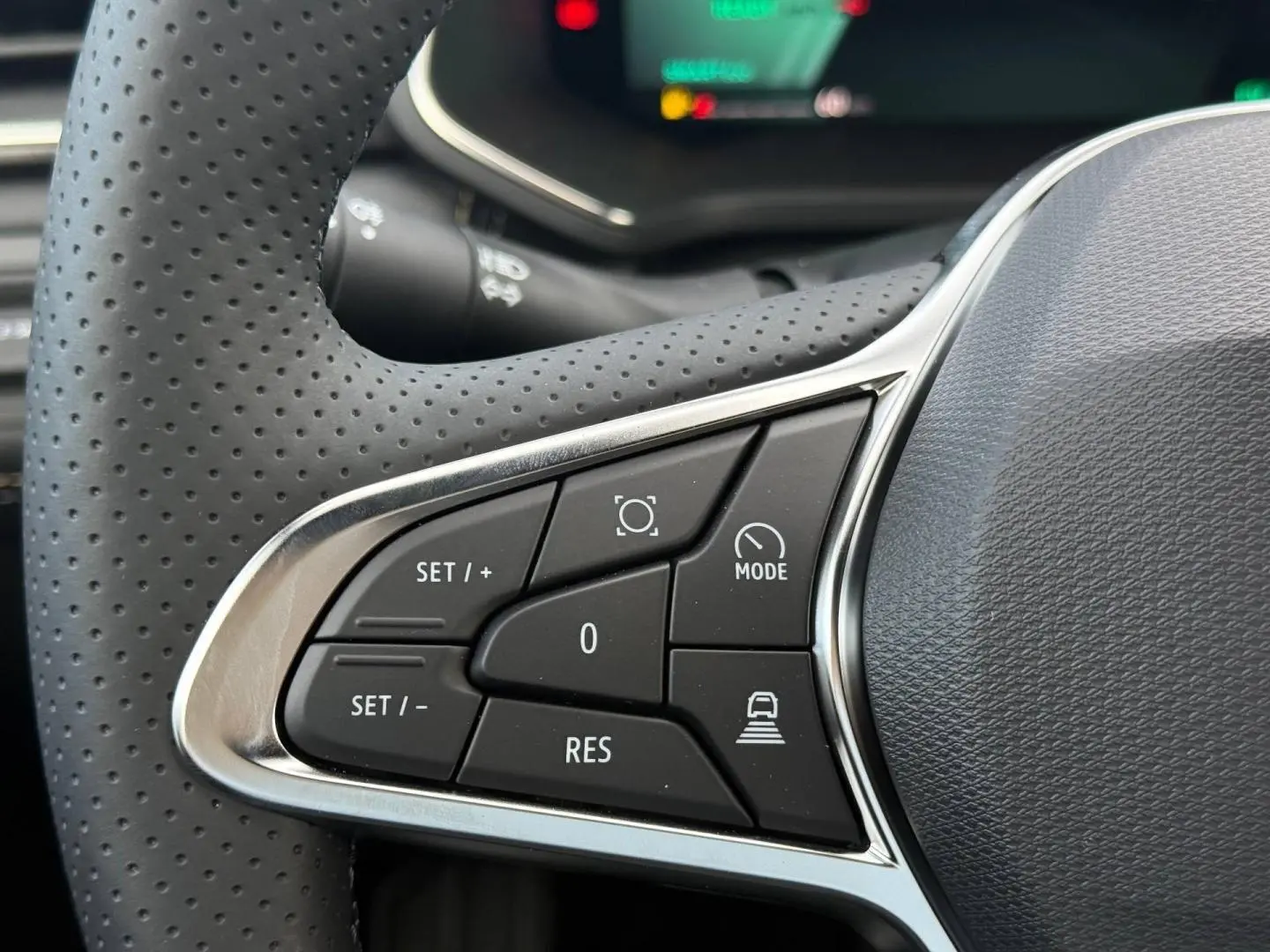 Gros plan sur les commandes multifonctions côté gauche du volant perforé du Renault Symbioz gris Rafale.