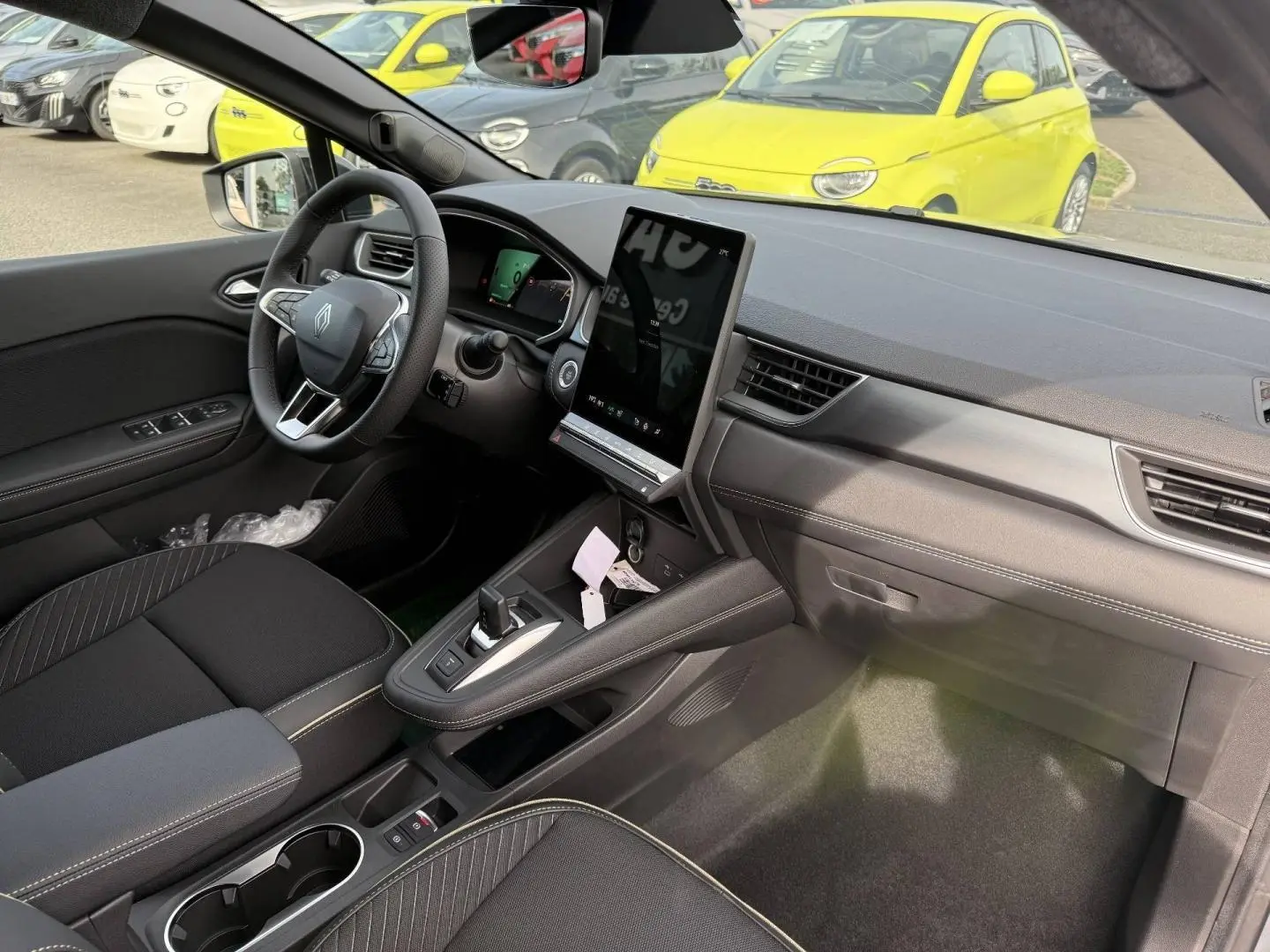 Intérieur avant du Renault SYMBIOZ gris Rafale, vue côté conducteur avec écran tactile vertical et volant multifonction.