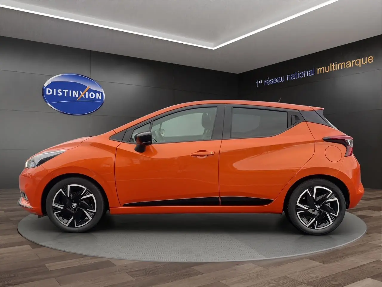 Vue latérale droite d'une Nissan Micra 2022 orange Energy avec jantes noires et détails noirs sur les bas de caisse.