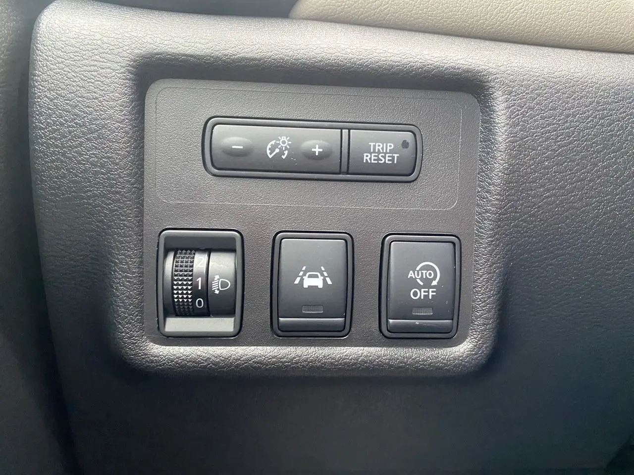 Panneau de commandes noir mat avec réglage luminosité, bouton de suivi de voie et désactivation automatique, intérieur Nissan Micra 2022.