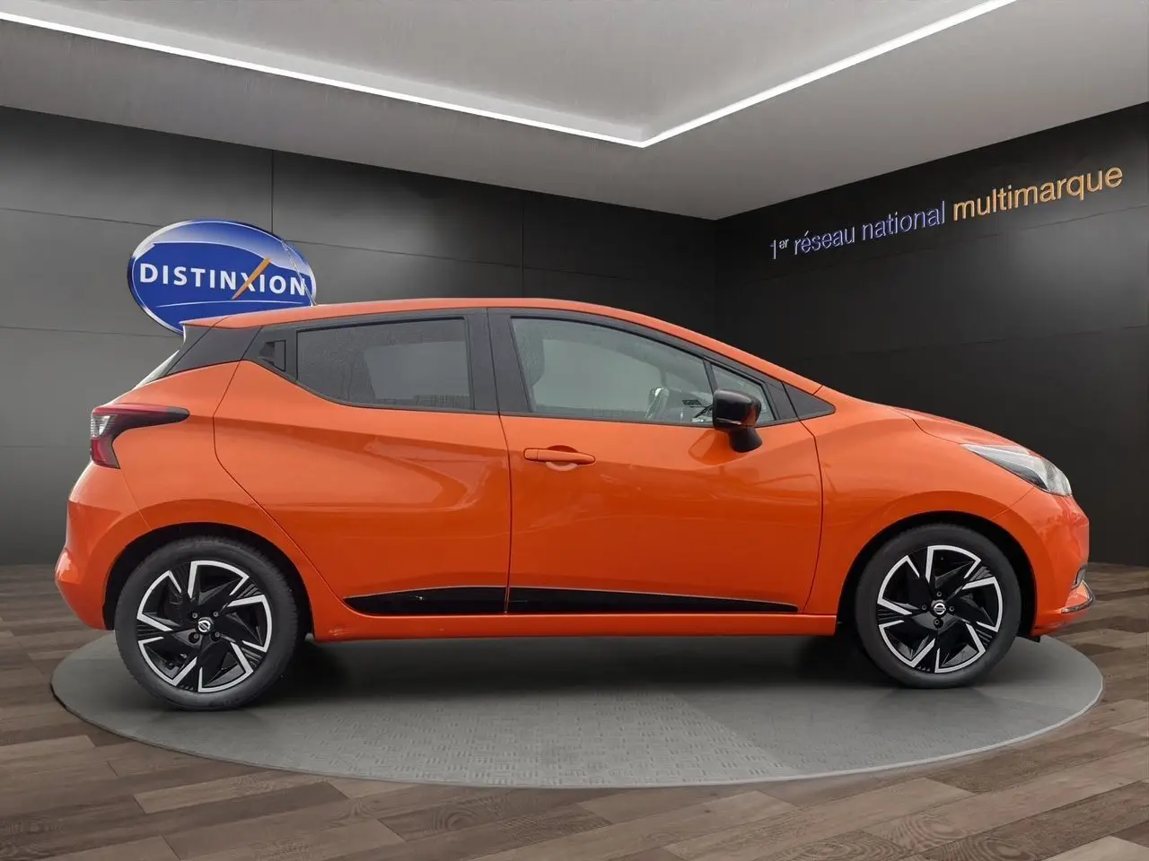 Vue latérale droite d'une Nissan Micra 2022 orange Energy avec jantes noires et détails noirs sur les bas de caisse.