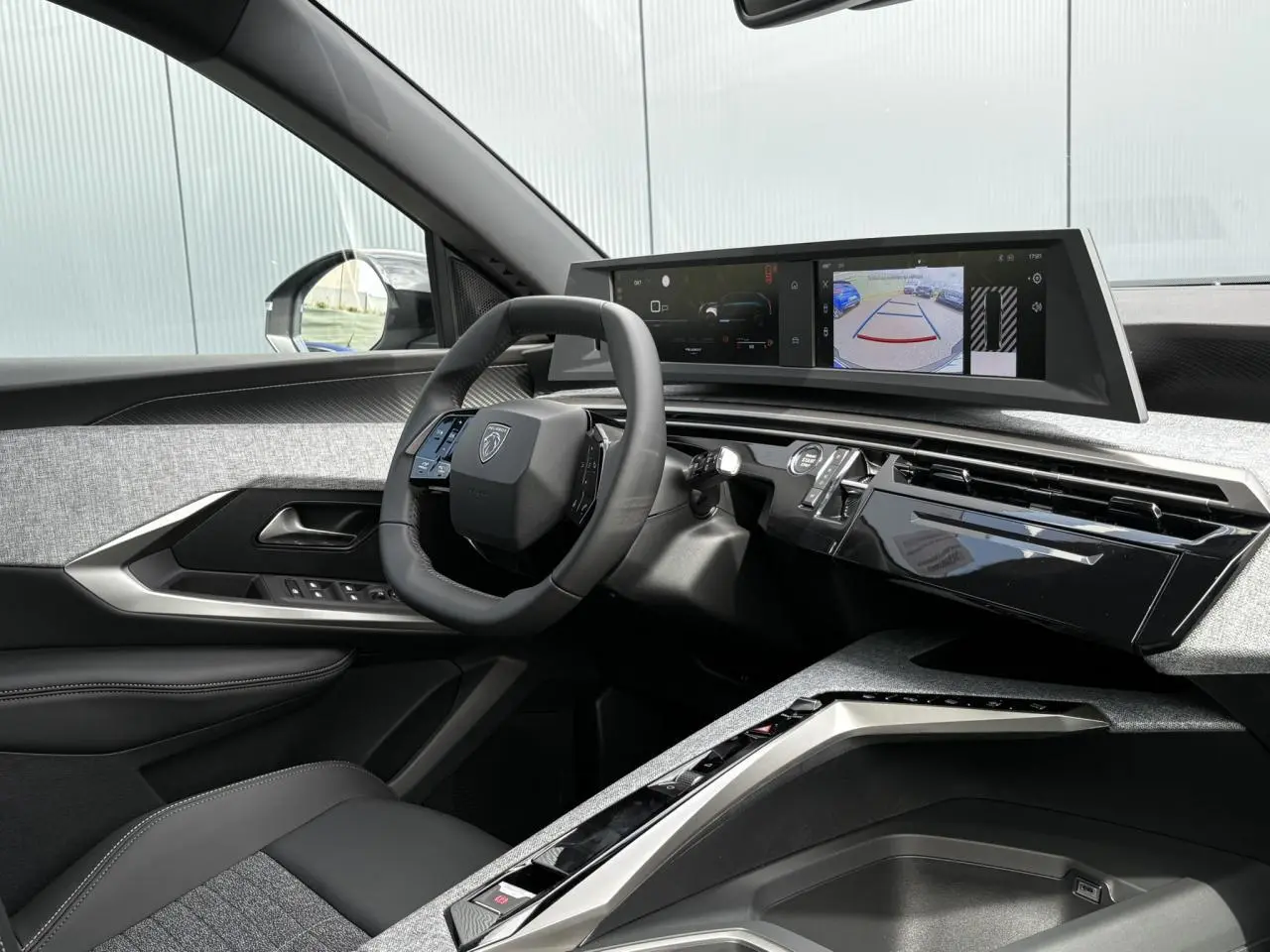 Vue intérieure côté conducteur du Peugeot 5008 Hybrid 2025, avec tableau de bord numérique et volant compact noir.