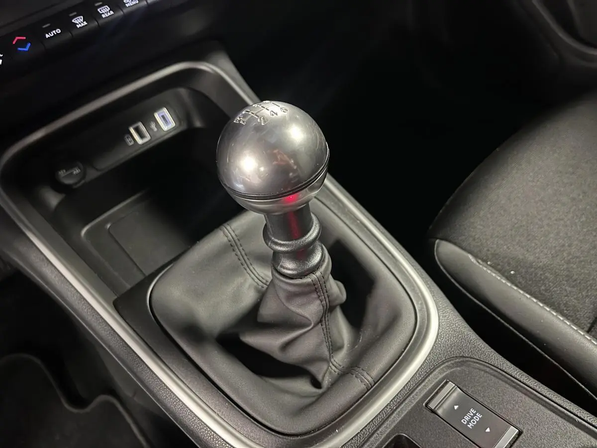 Gros plan sur le levier de vitesses manuel en TEP noir du Jeep Avenger 2024, avec console centrale et prise USB visible.