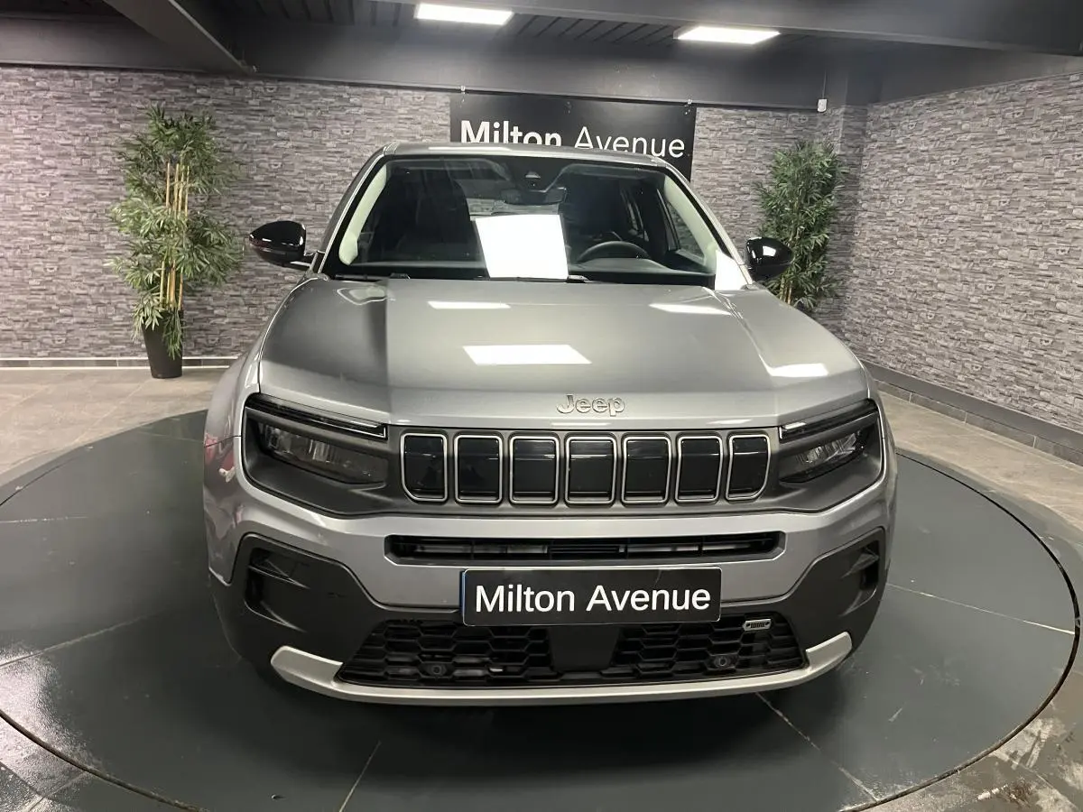 Vue frontale du Jeep Avenger gris métallisé avec calandre distinctive et coques de rétroviseurs noires brillantes.