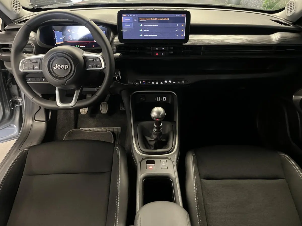 Intérieur du Jeep Avenger 2024 en vue frontale, volant Jeep, tableau de bord numérique et levier de vitesse manuel.