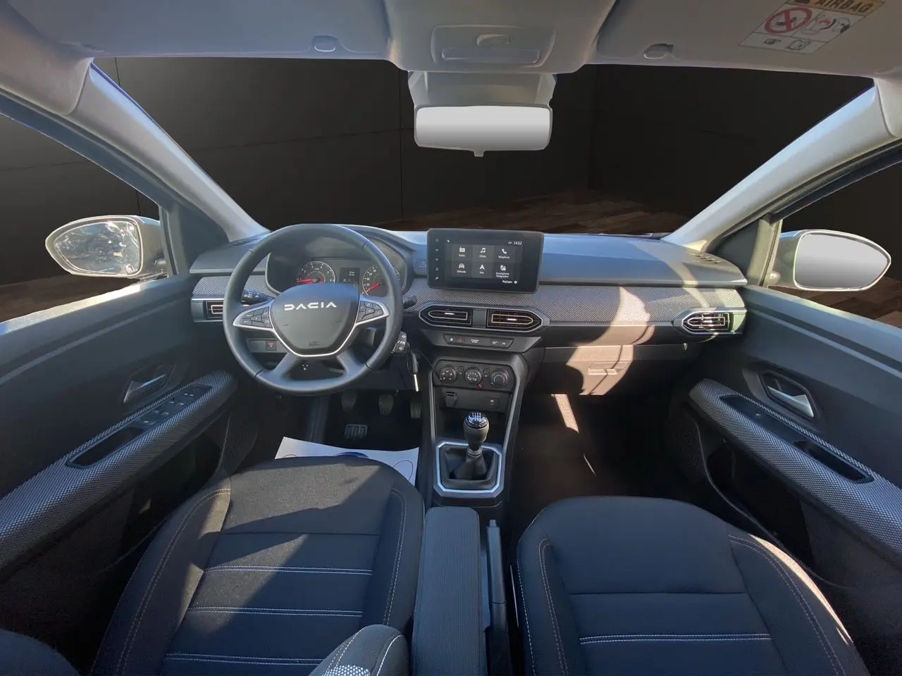 Vue intérieure avant de la Dacia Sandero Stepway 2025, tableau de bord noir avec écran tactile Media Nav et volant multifonction.