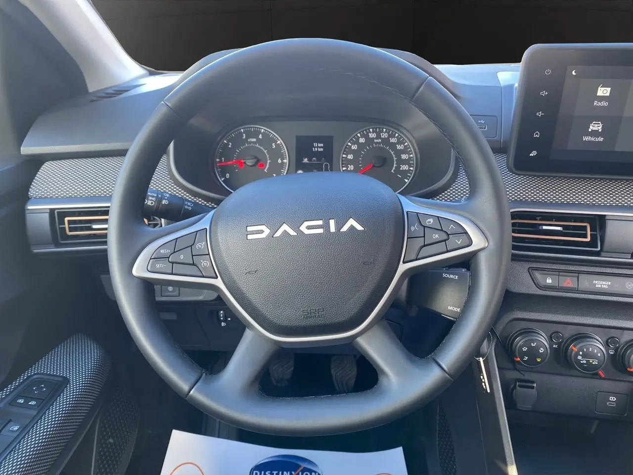 Vue rapprochée du volant noir DACIA avec tableau de bord et écran tactile du Media Nav en arrière-plan.