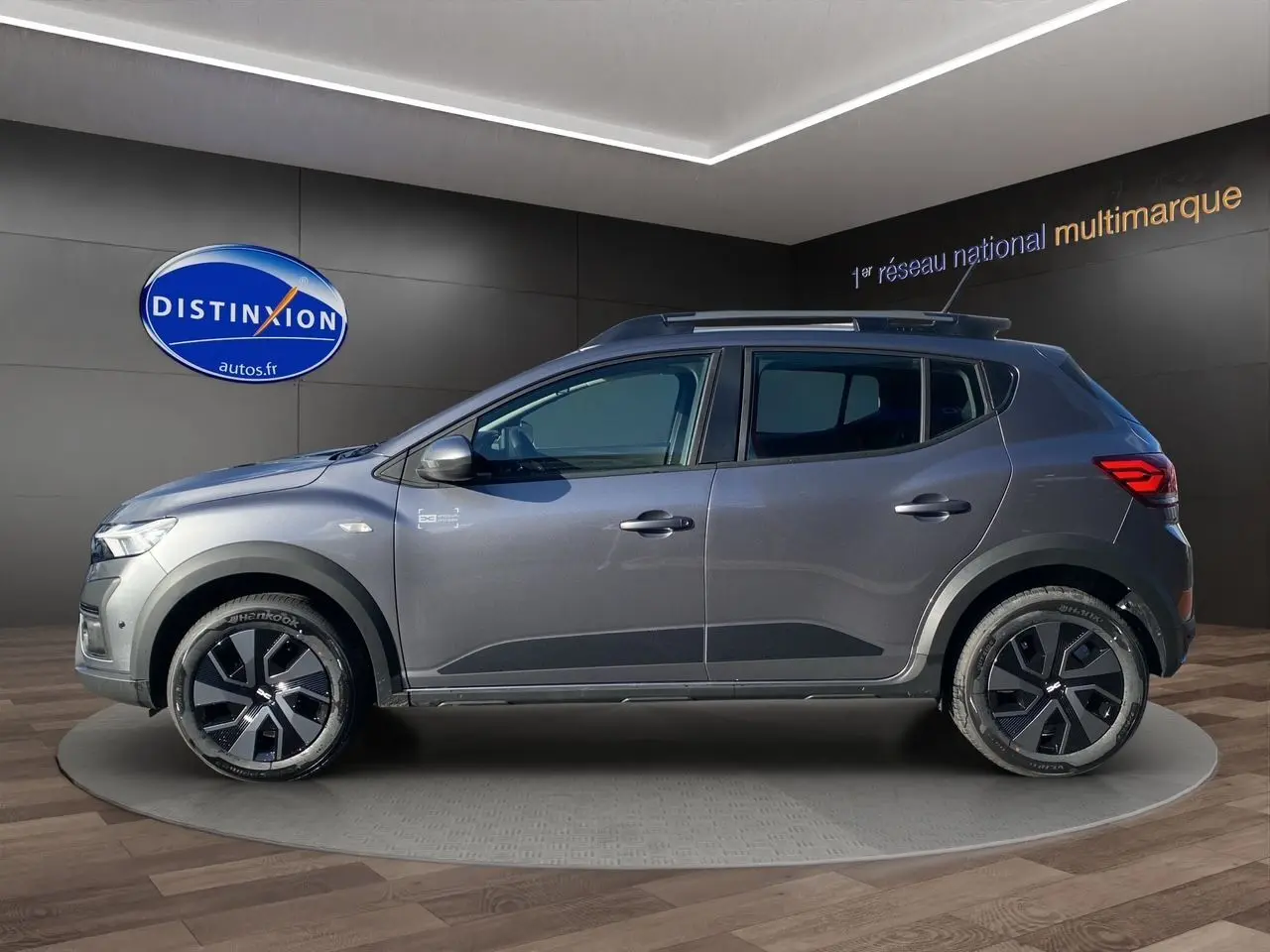 Profil droit d'une Dacia Sandero Stepway 2025 gris schiste avec barres de toit et jantes noires distinctives.