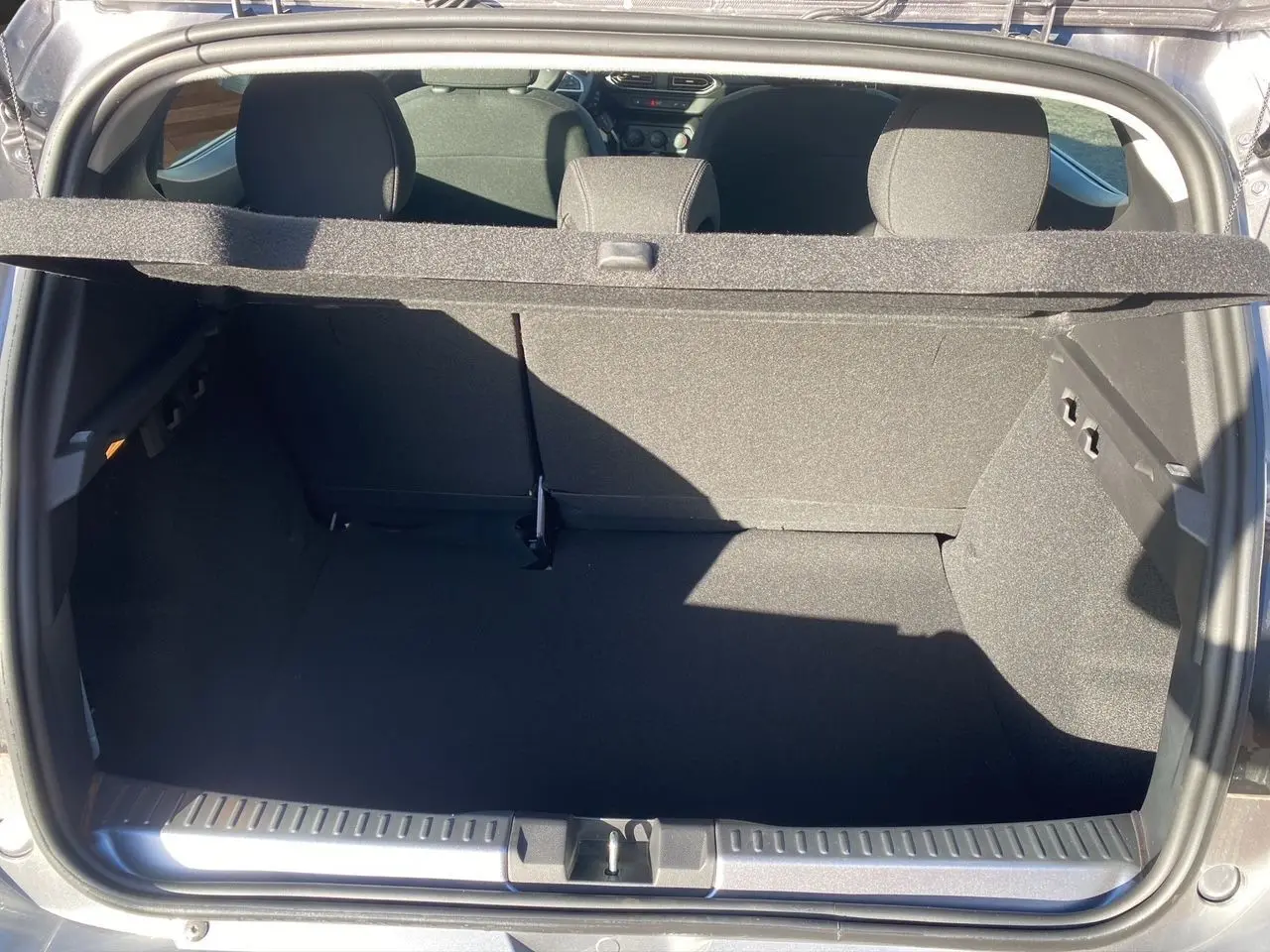 Coffre ouvert d'une Dacia Sandero Stepway gris schiste, vue arrière montrant l'espace de chargement et la banquette arrière.