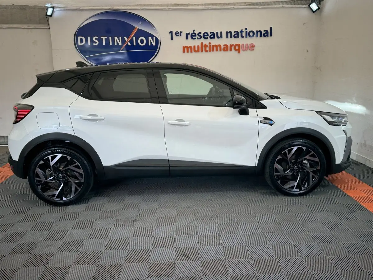 Profil droit d'un Renault Captur blanc esprit Alpine E-Tech 145 hybride avec toit noir et jantes noires stylisées.
