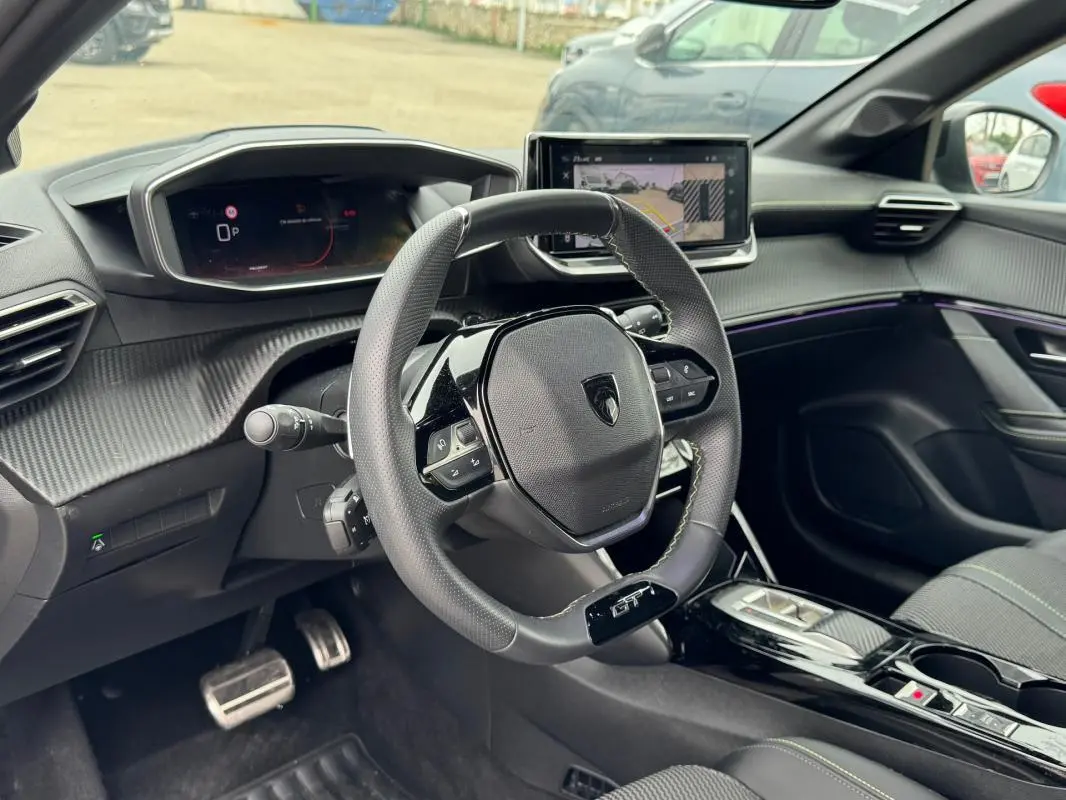 Vue intérieure côté conducteur du Peugeot 208 Hybrid 110 e-DCS6 GT 2025, volant compact GT et écran tactile central.