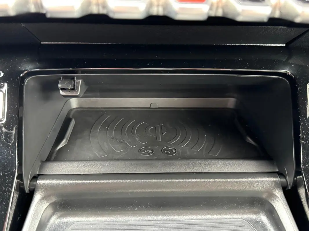 Gros plan sur le compartiment de recharge sans fil du Peugeot 208 Hybrid 110 e-DCS6 GT gris, intérieur noir.