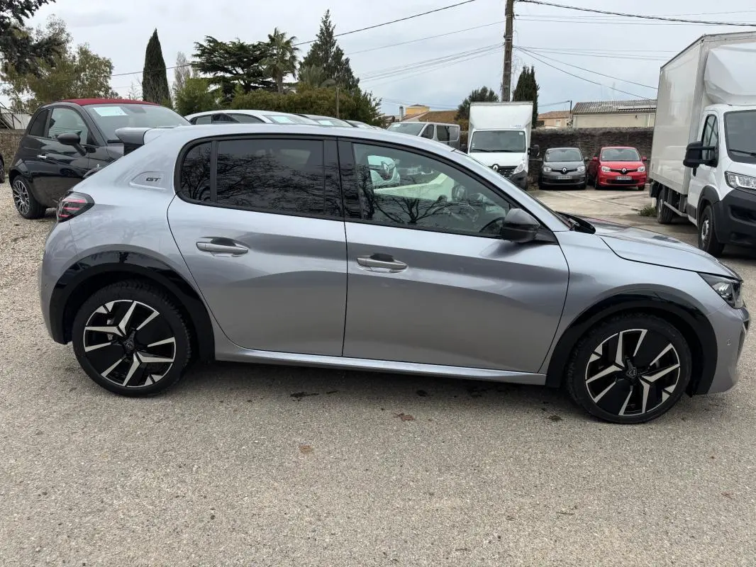 Profil droit d'une Peugeot 208 Hybrid 110 e-DCS6 GT gris avec jantes alliage 17 pouces et vitres teintées.