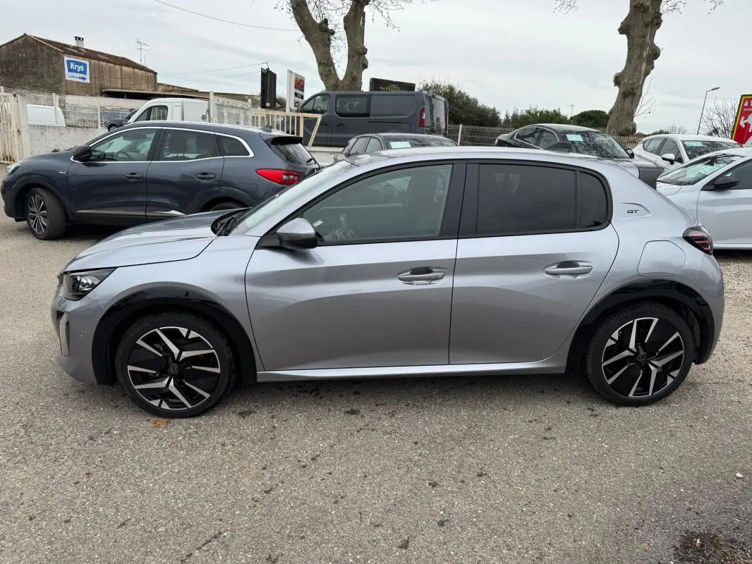 Vue de profil côté gauche d'une Peugeot 208 gris métallisé Hybrid 110 e-DCS6 GT avec jantes alliage 17 pouces et antenne requin.