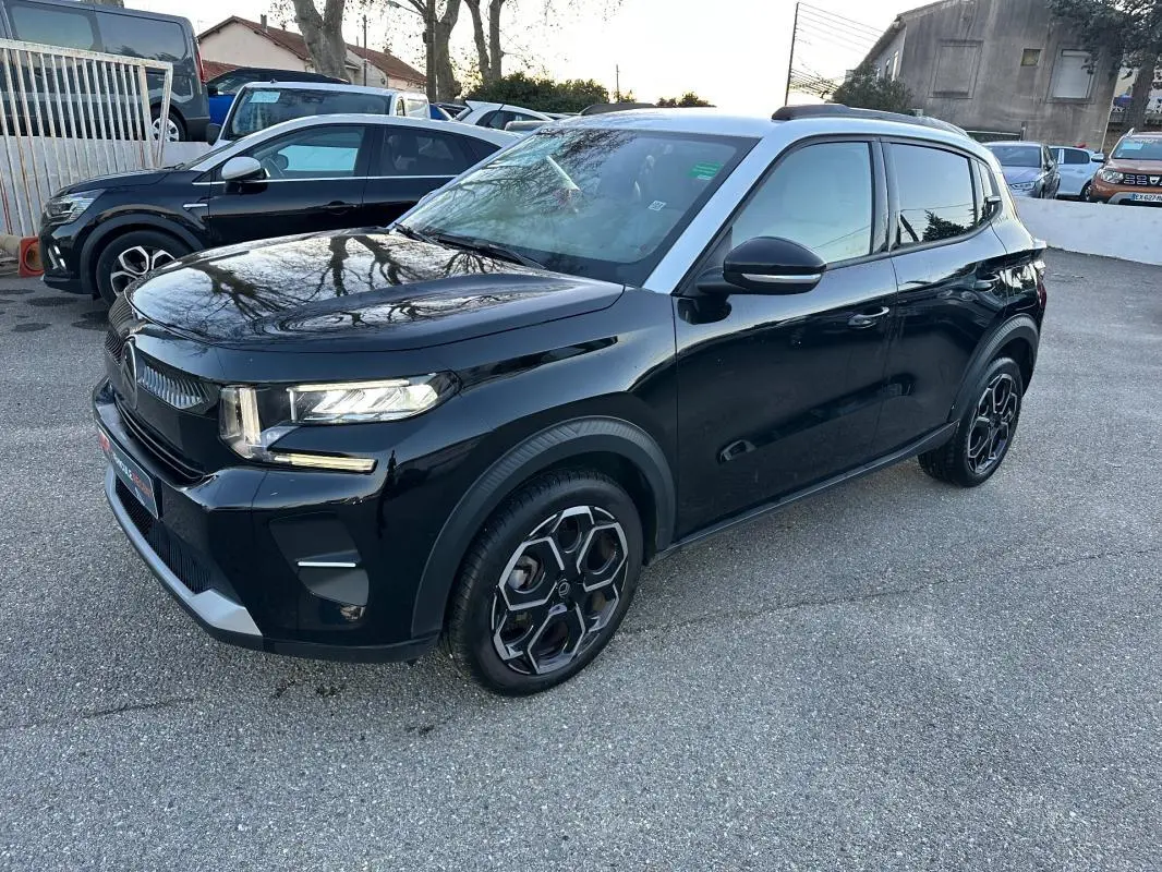 Vue 3/4 avant droite d'une Citroën C3 noire 2025 avec jantes alliage 17 pouces et barres de toit visibles.