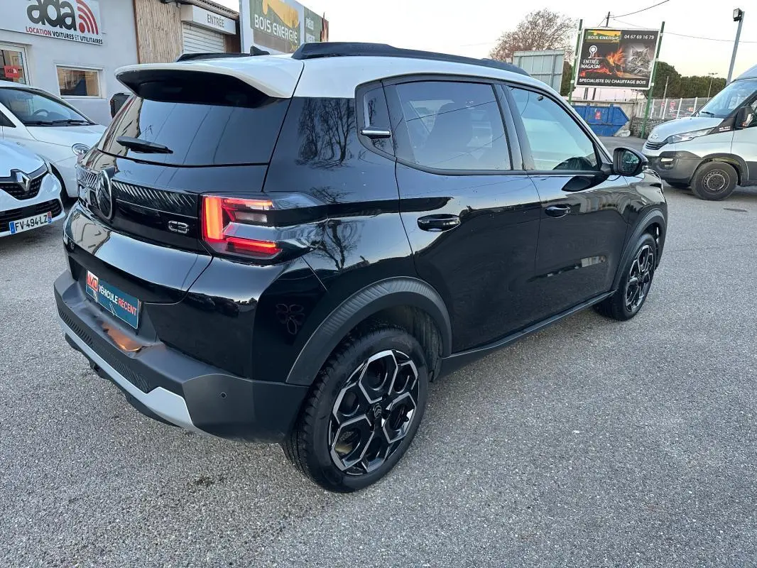 Vue 3/4 arrière droite d'une Citroën C3 noire 2025 avec barres de toit et jantes alliage 17 pouces.