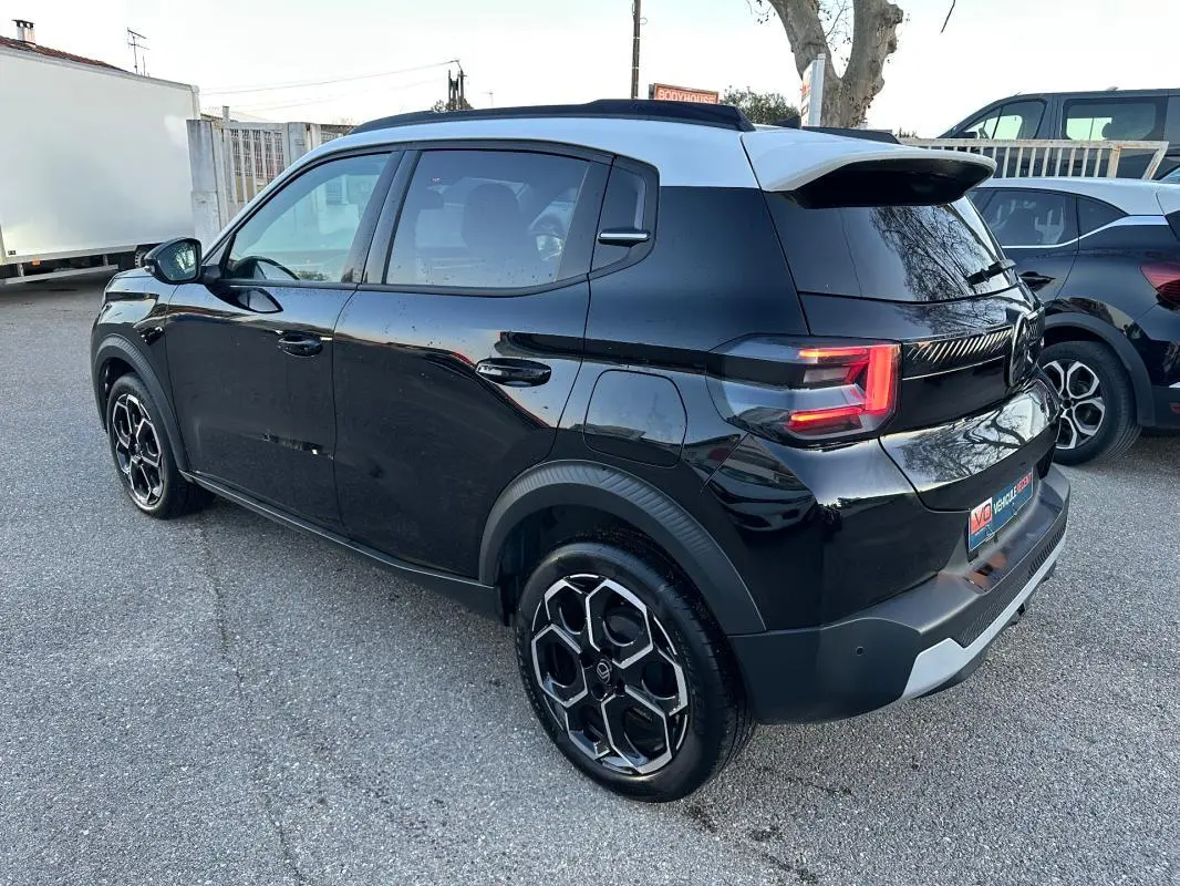 Vue 3/4 arrière droite d'une Citroën C3 Turbo noire avec jantes alliage 17 pouces et barres de toit visibles.