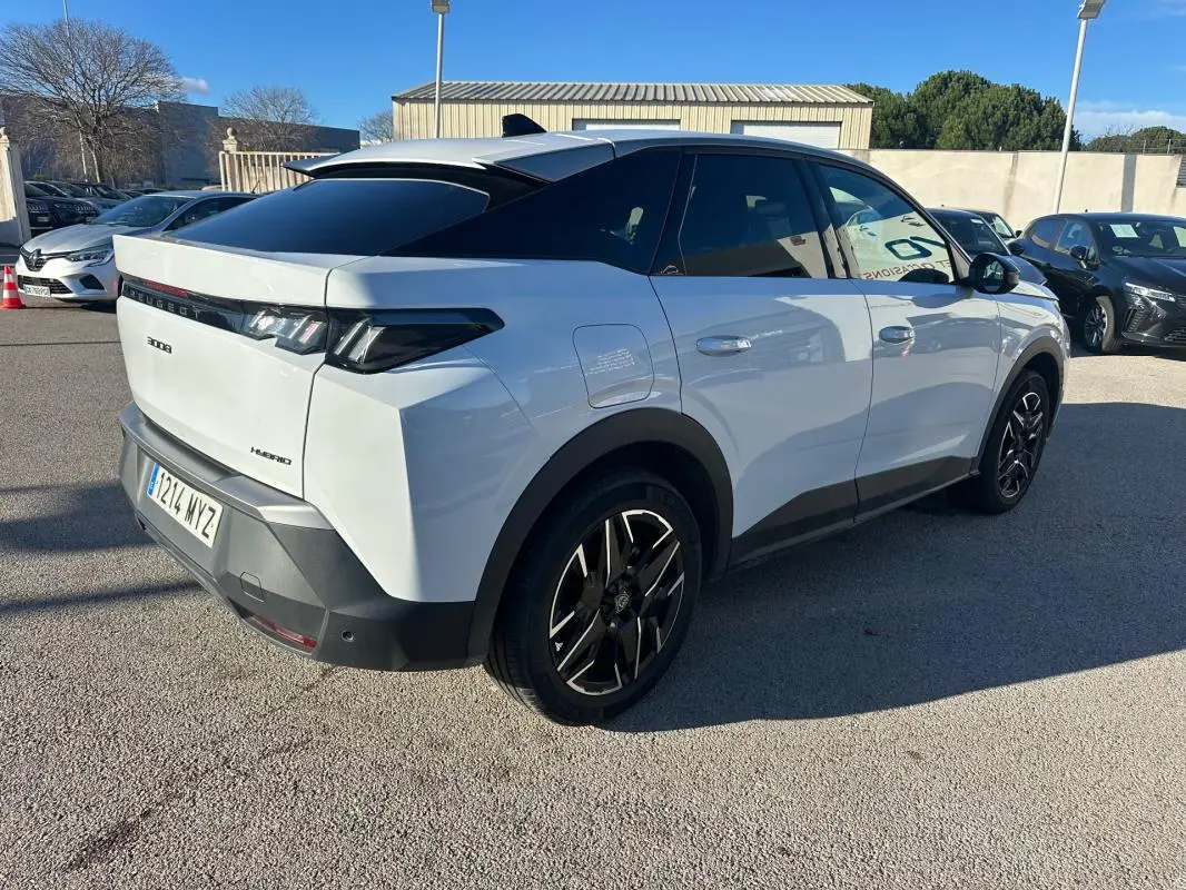 Vue 3/4 arrière droite d’un Peugeot 3008 Hybrid blanc avec jantes alliage noires 19 pouces et toit noir.