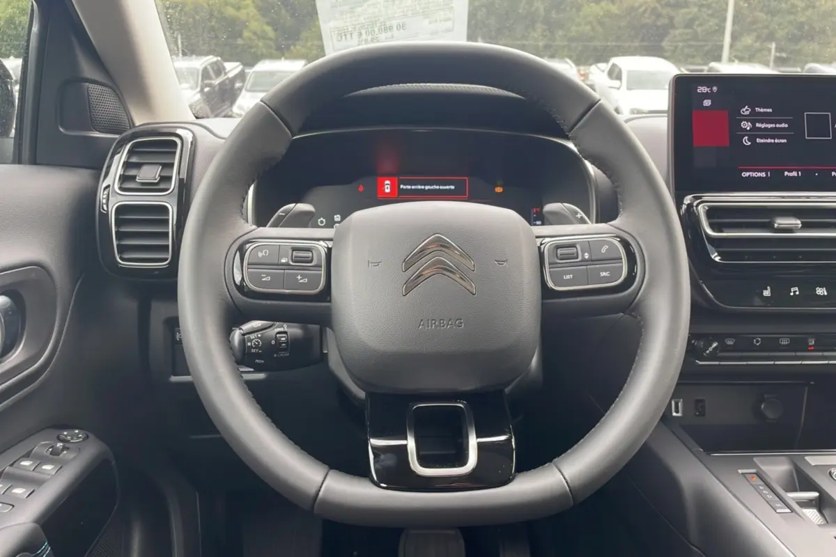 Vue intérieure centrée sur le volant du Citroën C5 Aircross Hybrid 2025 avec tableau de bord numérique et écran tactile.