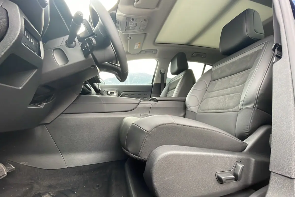 Intérieur avant du Citroën C5 Aircross Hybrid 2025, sièges en cuir noir et toit ouvrant panoramique visible.